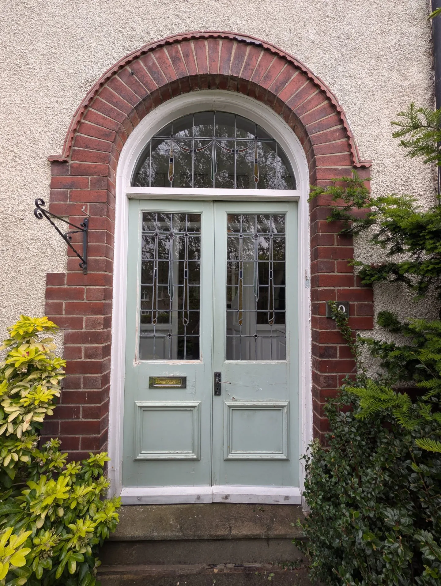 Arched double entrance doors before repainting, finished in pale grey