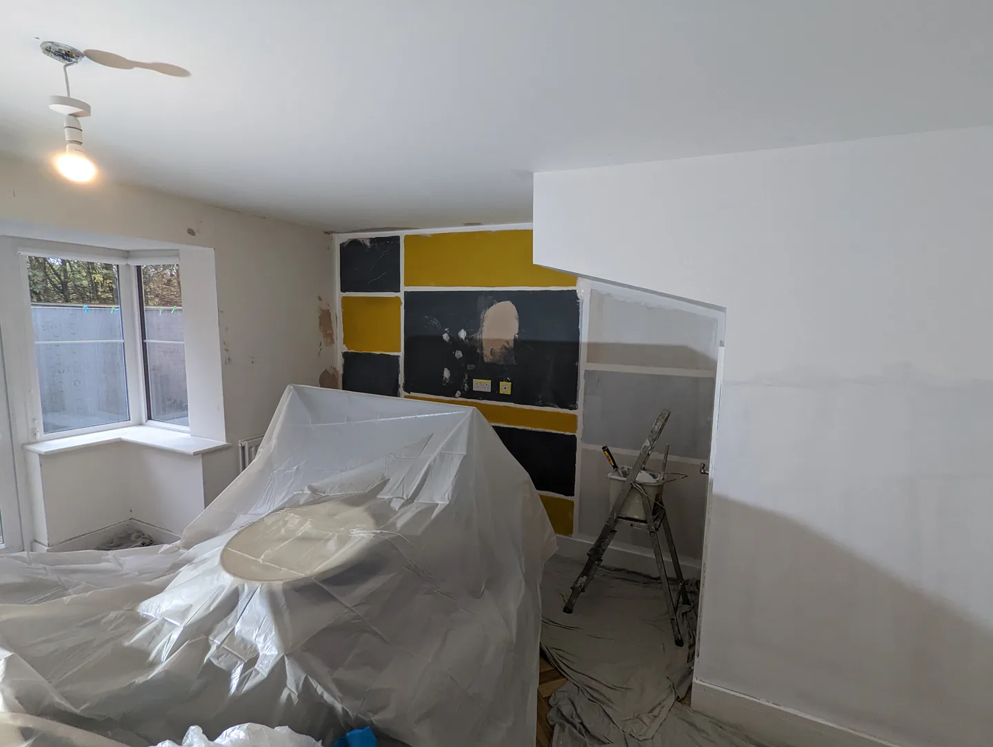 Lounge during redecoration, with furniture covered and a feature wall being prepared