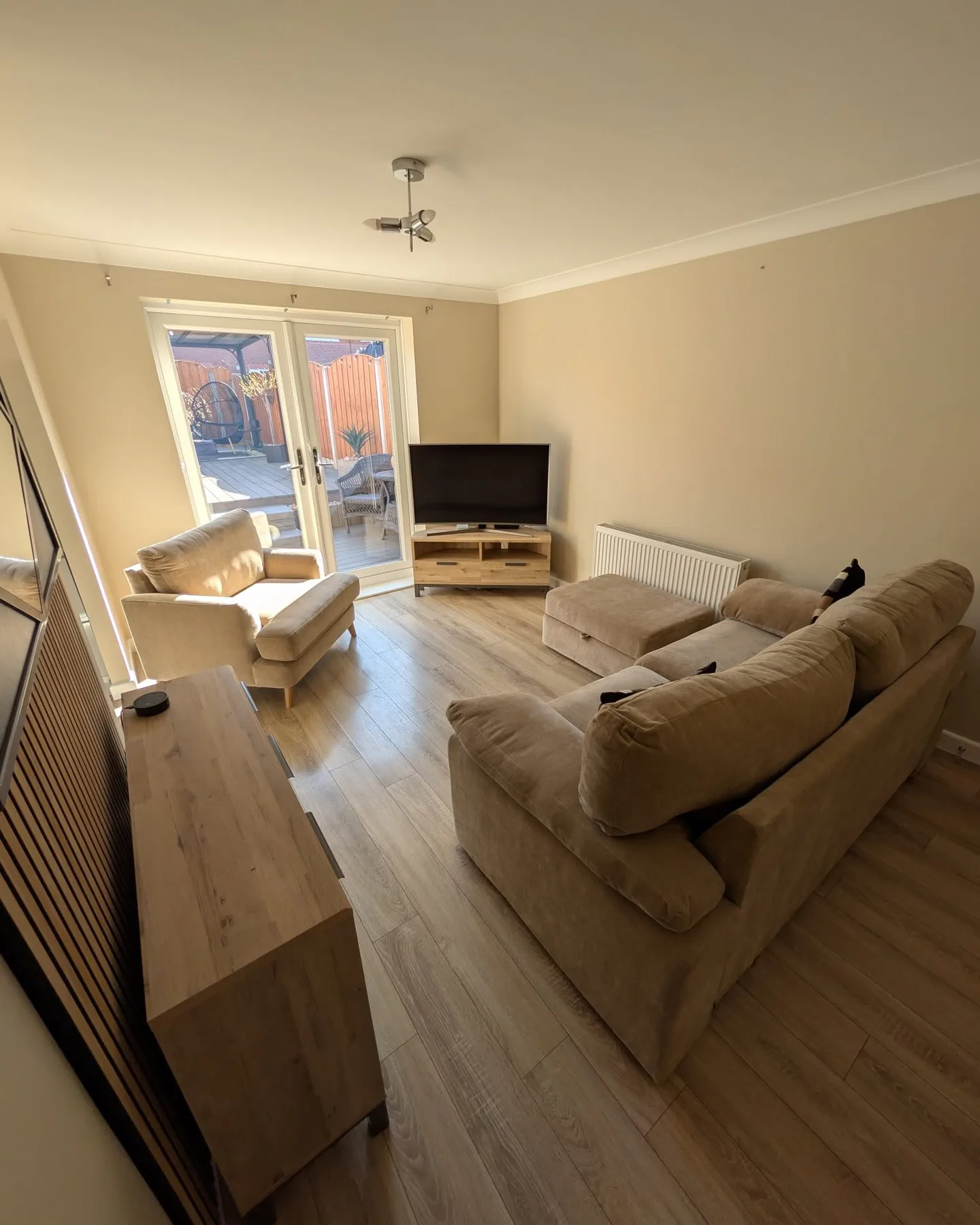 Neutral lounge with warm beige walls, wood flooring and garden doors
